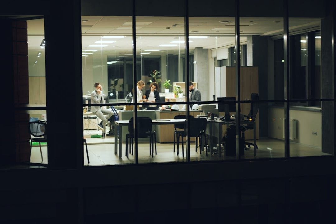 Espace de travail éclairé où une équipe collabore dans un environnement de bureau moderne la nuit.